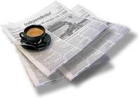 Newspaper sections folded and stacked, with a cup of morning coffee